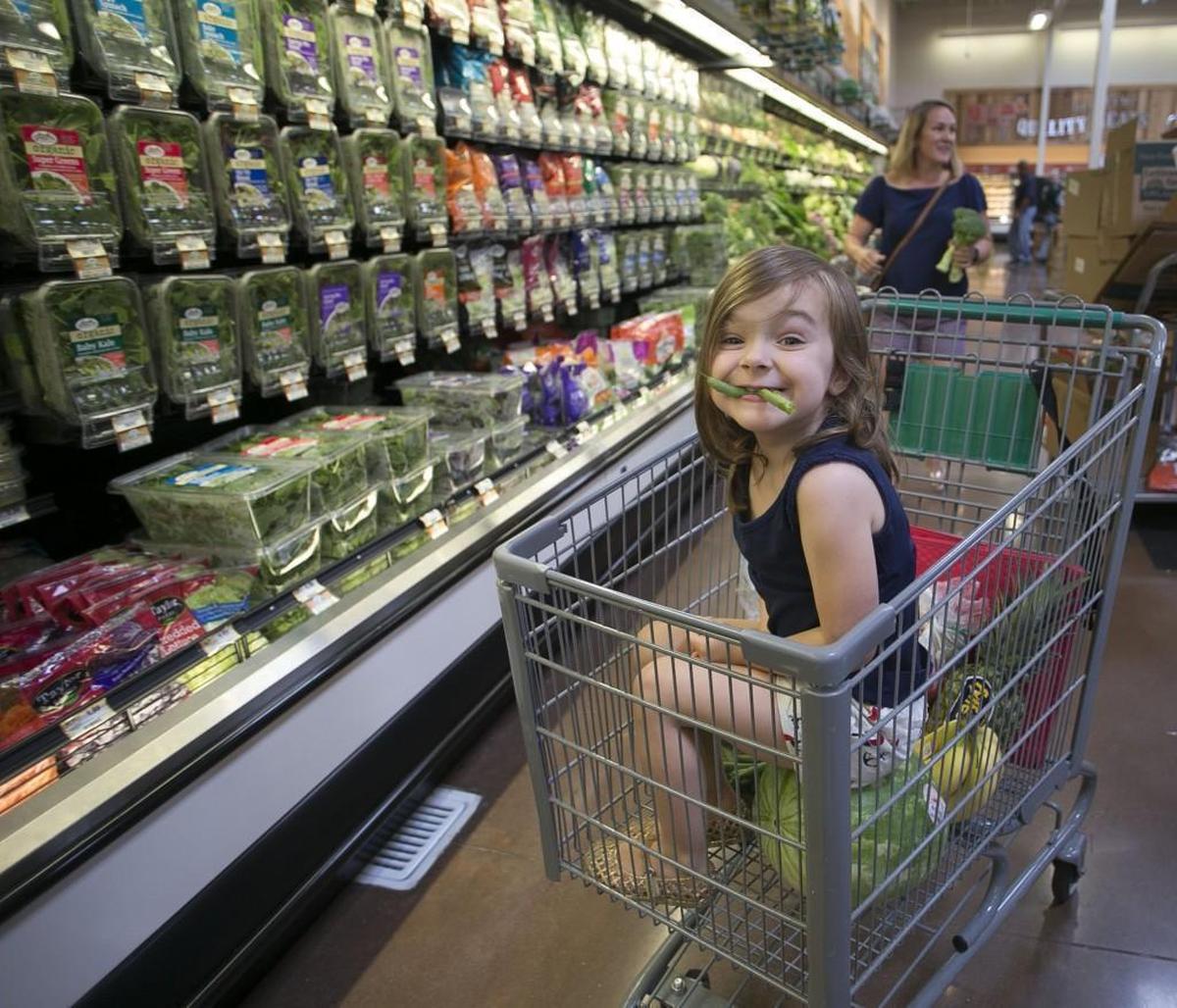 Four-year-old Peyton Gilreath of Raleigh munches on a green bean as she rides in the shopping cart with her mother at the new Sprouts Farmers Market grocery store on Falls of Neuse Road in Raleigh.