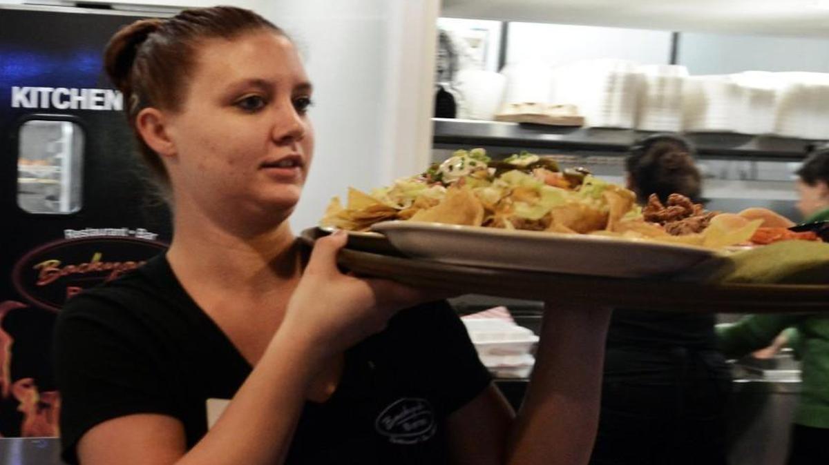 Brittany Barnes carries a tray of food to a table during lunch at the Backyard Bistro restaurant across from the PNC Arena in Raleigh, N.C., in this file photo from 2012. There will be a job fair for hotel and restaurant workers at the Raleigh Convention Center in March 2018 to help address a shortage of workers in the hospitality industry.