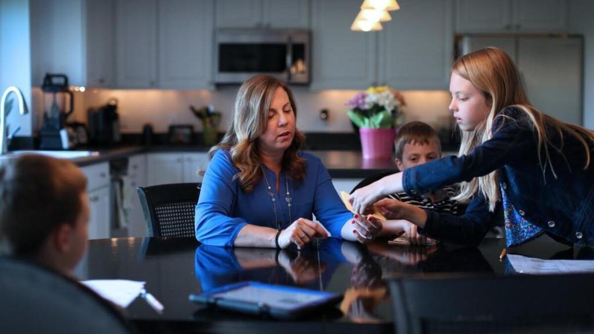 Brooke Bleyl, who took ten years off working to care for her children and has recently returned to the workforce, goes over homework with her children, from left, Evan, Jayce and Ella, at home in Twinsburg, Ohio, May 18, 2016. Though many women follow “don’t ask, don’t tell” when job-seeking after a child care gap, new a study says it may be better to explain why they stayed home rather than stay silent.