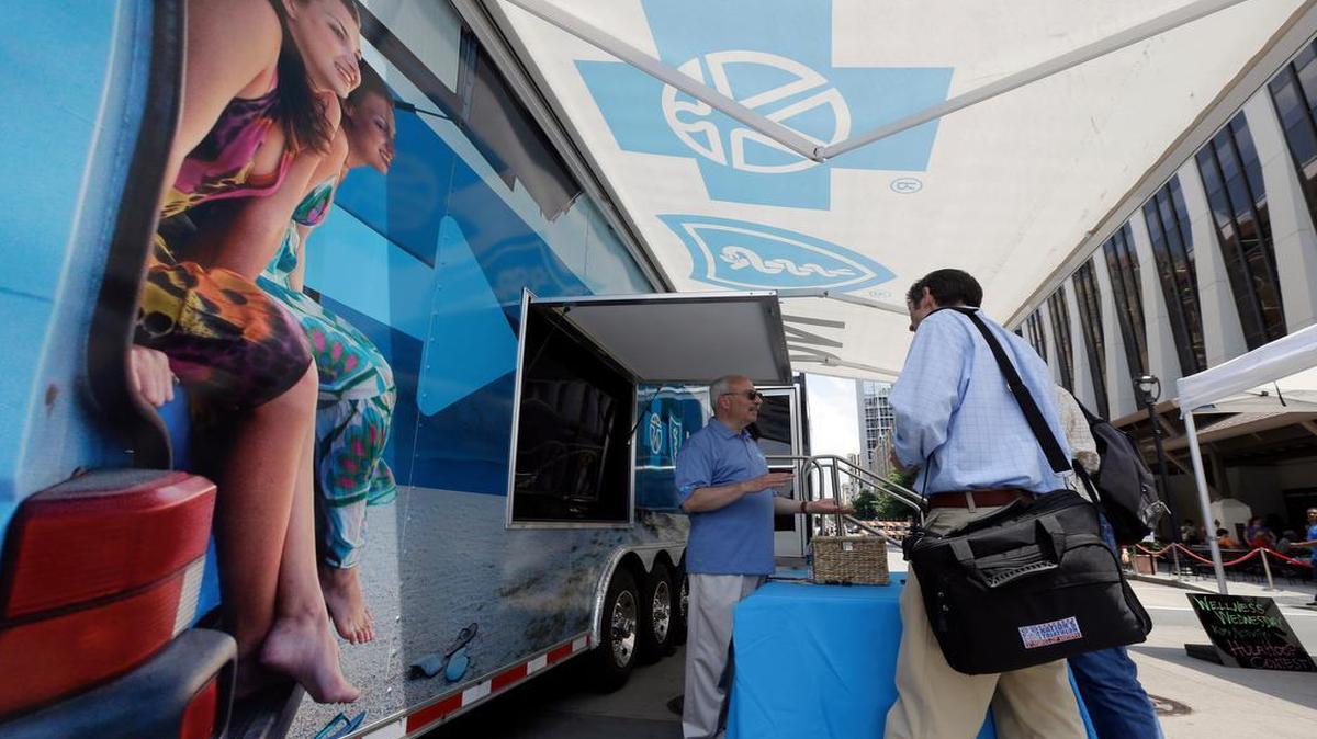 
Blue Cross Blue Shield of North Carolina employee Lew Borman, left, helps a customer outside a trailer at the downtown farmer's market in Raleigh. BCBS is eligible for nearly $295 million in federal payouts under the Affordable Care Act, even as the company is seeking another rate increase in the state.
