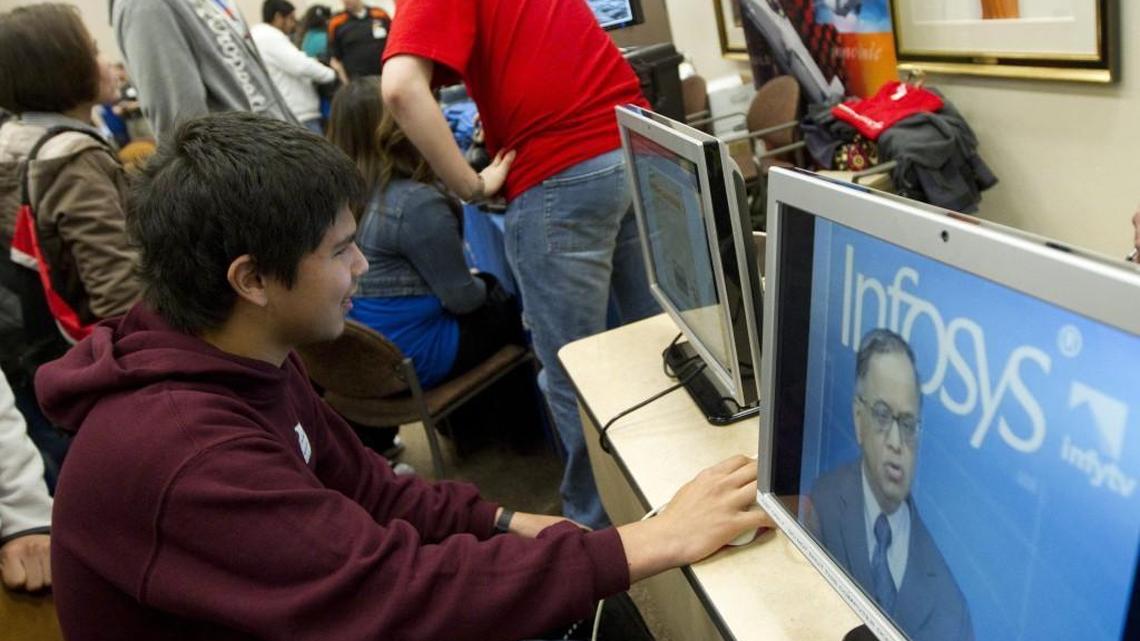 Infosys has in the past partnered with high schools to teach students about technology jobs. In this file photo a student looks at an Infosys display during a Technology Awareness Day.