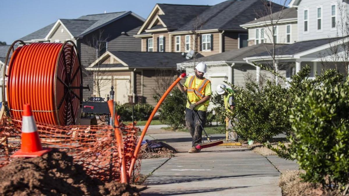 Contractors Bryan Secord, foreground, and Herb Bergman sweep clay from a sidewalk as crews lay fiber optic lines for high speed internet Tuesday, December 15, 2015 on Seymour Place in Cary. Some residents have complained that workers are making a mess of the right of ways as they install the networks.