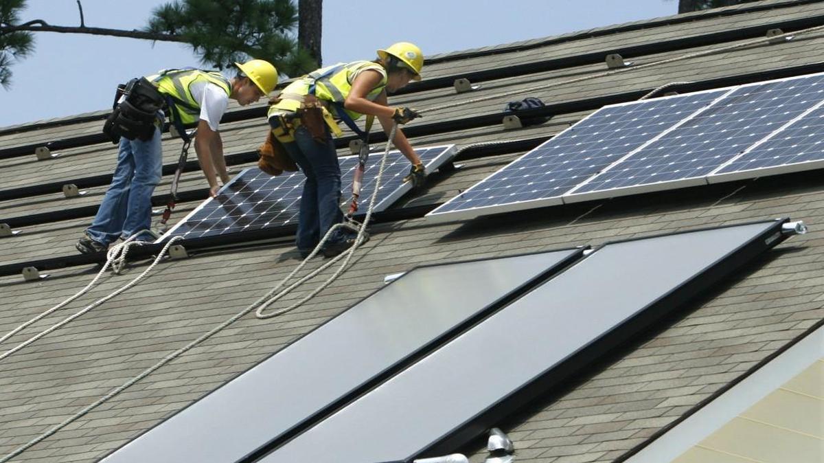 Workers install solar panels on a roof in North Carolina in this file photo. POWERHOME, a solar panel company, is opening an office in Raleigh and will bring 100 jobs to the area.