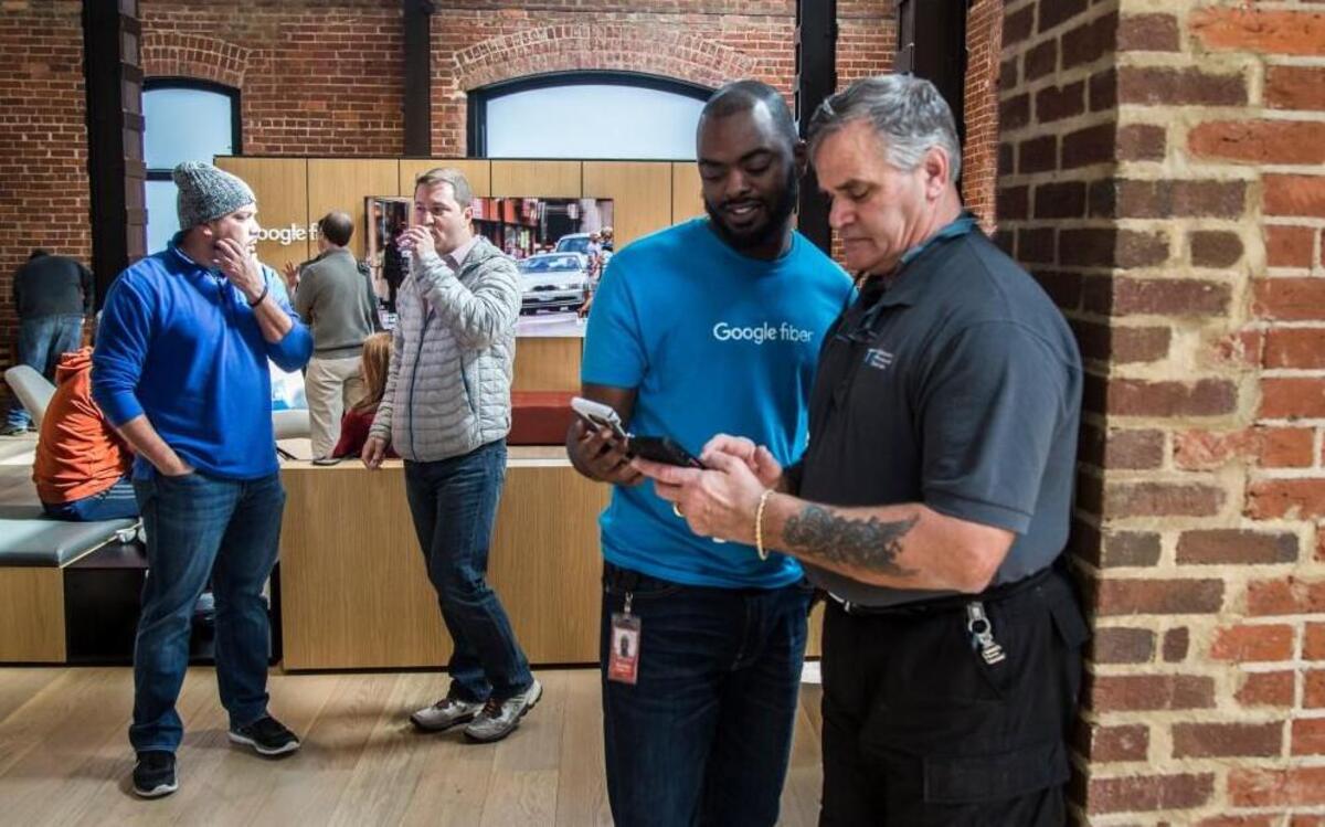 Customer service representative Quintin Royster, left, demonstrates Google Fiber speeds on Joel Clarke's phone during the grand opening of the Raleigh Fiber Space Wednesday, Feb. 1, 2017 in the 518 West Jones building in Glenwood South. The Fiber Space is a communal space where the public can try out free gigabit speed internet. Google Fiber is accepting sign-ups for residents and businesses in the North Hills and midtown area of Raleigh with more service arriving in Raleigh in the coming years.