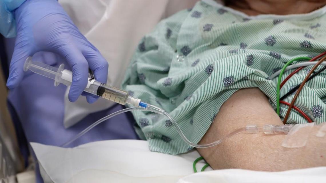 A nurse administers an IV push of antibiotics to a patient. Many hospitals are using means other than saline bags to administer medicine to patients because of a shortage of the bags.