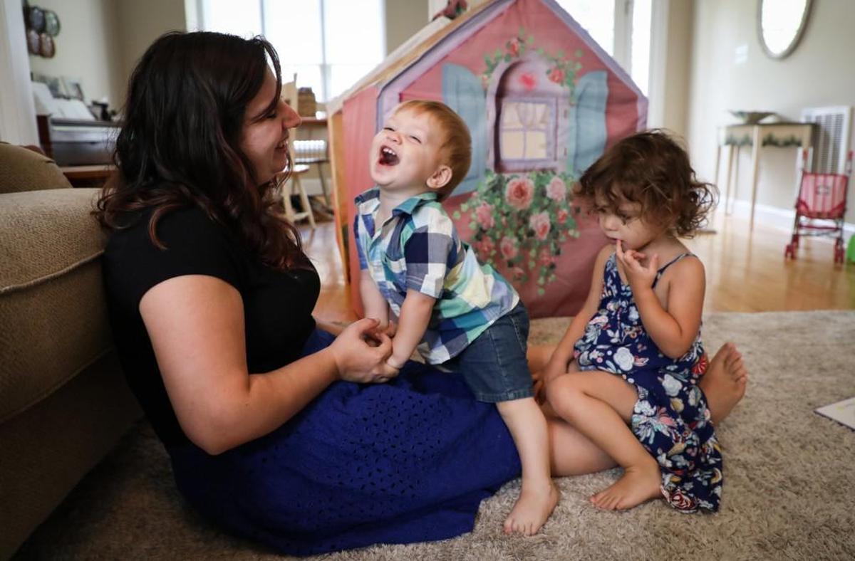 Kim Swanson plays with her son Sammy, 13 months, and daughter Marley, 3, after reading books in their living room. Swanson lost her job after Marley was born because her employer didn’t meet the requirements of the Family and Medical Leave Act. She supports efforts to require paid parental leave, but not if jobs aren’t protected.