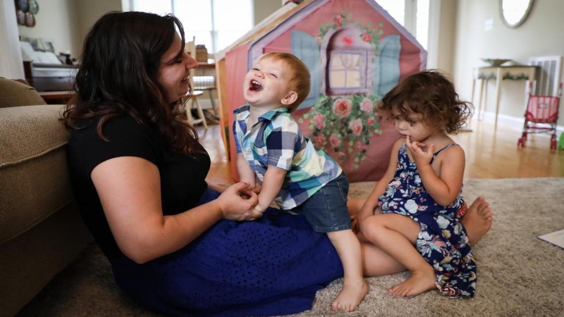 Kim Swanson plays with her son Sammy, 13 months, and daughter Marley, 3, after reading books in their living room. Swanson lost her job after Marley was born because her employer didn’t meet the requirements of the Family and Medical Leave Act. She supports efforts to require paid parental leave, but not if jobs aren’t protected.