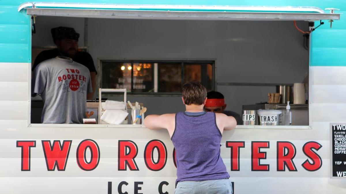 A customer buys ice cream from Two Roosters Ice Cream during a concert event in downtown Raleigh on July 21.