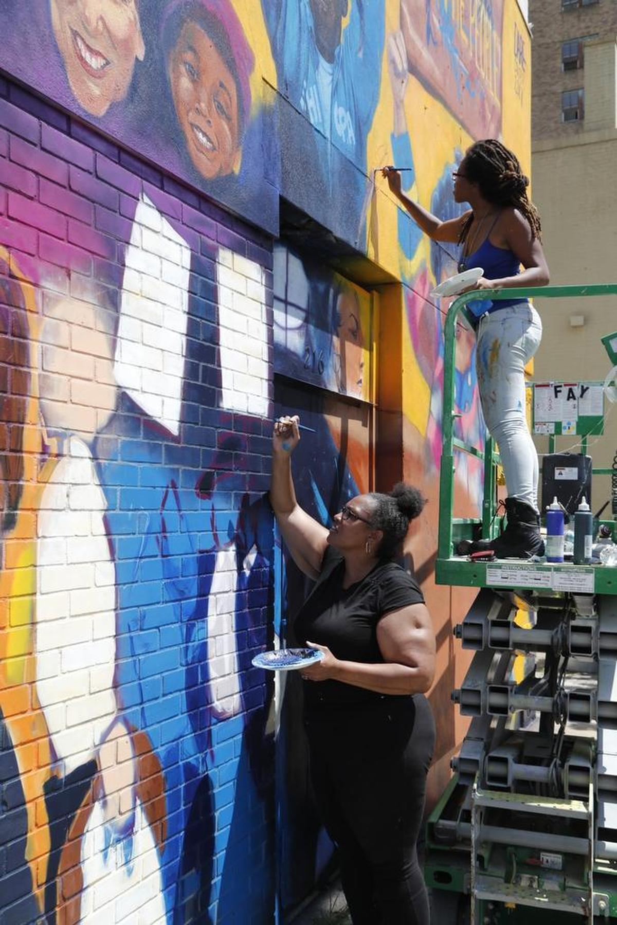 Artist Dare Coulter, top, and her mother Anita Coulter, paint a mural of protestors as part of an ACLU commission on the back of a building on Salisbury St. in Raleigh, NC on June 27, 2017. It is slated to be unveiled Wednesday, June 28, 2017.