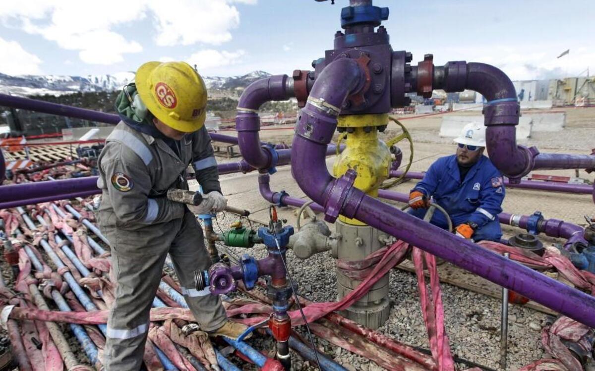 Workers tend to a well head during a hydraulic fracturing operation at an Encana Oil & Gas (USA) gas well outside Rifle, in western Colorado.
