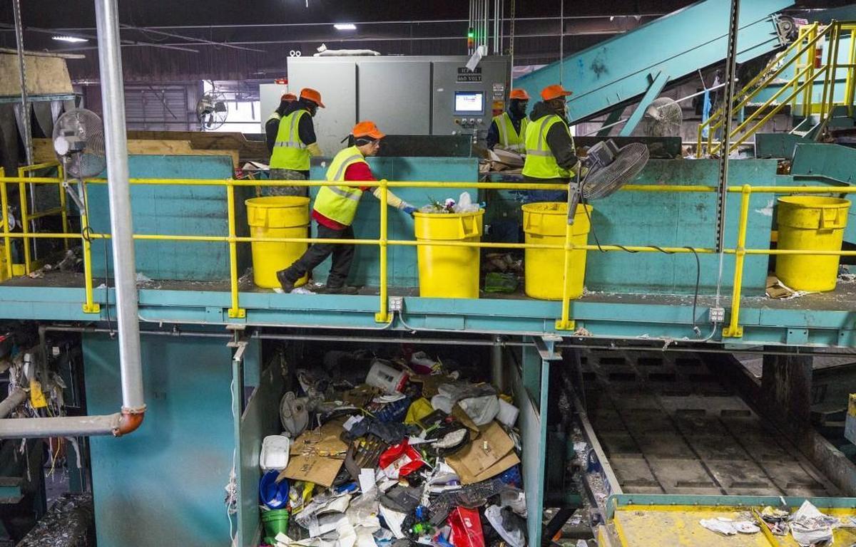 Carlos Acevedo, center, sorts incoming materials at the Sonoco Recycling facility in Raleigh.