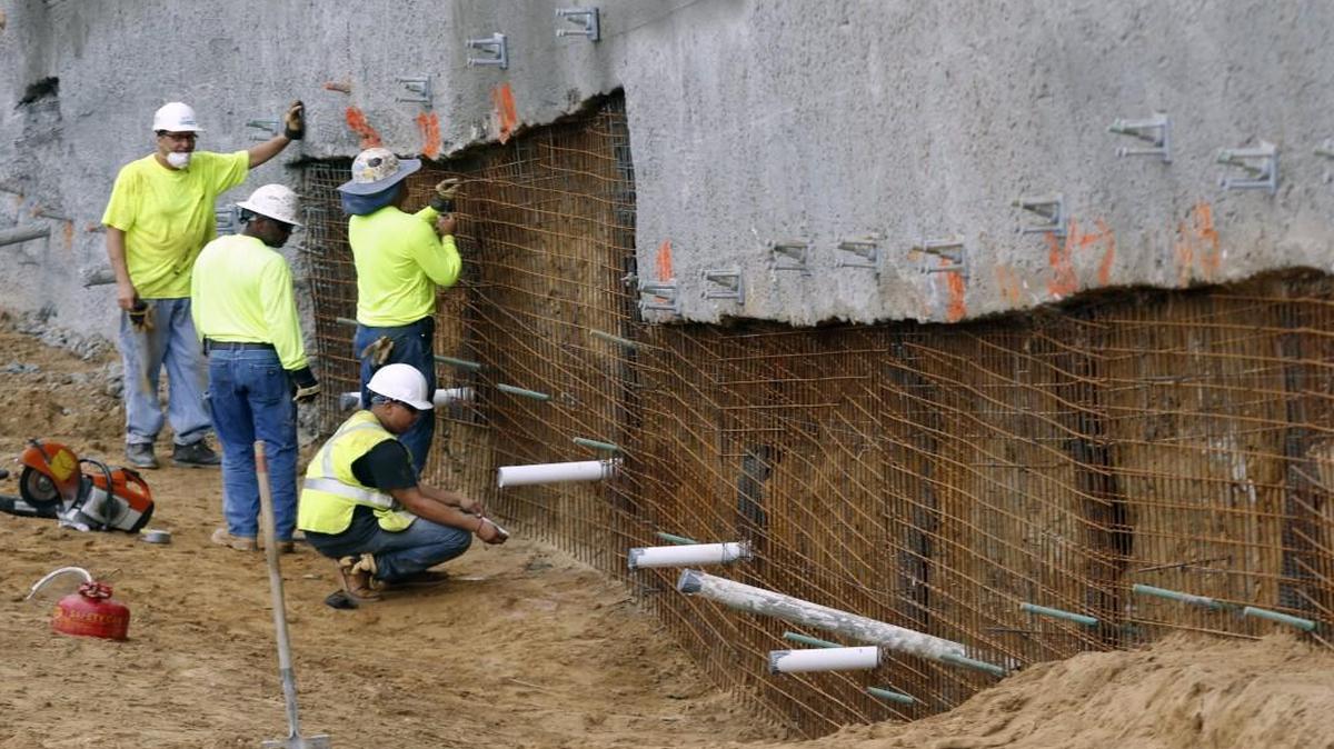 
Workers for Subsurface Construction Company of Raleigh, NC anchor sheets of wire mesh into an earth and stone wall Thursday, September 10, 2015 to be reinforced with shot concrete for the base of a retaining wall at the new Waltonwood at Lake Boone senior living facility. 
