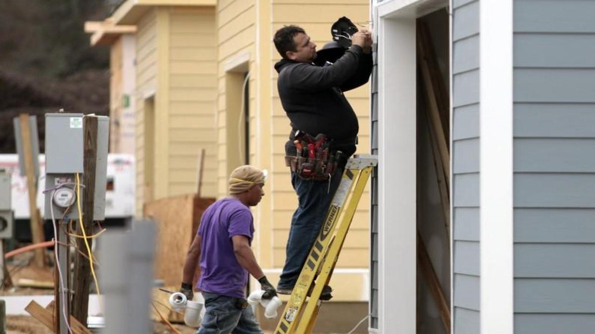 An electrician installs a rear exterior garage entry light on one of a row of new homes on Beardall Street being built out in the first phase of the new 5401 North subdivision Tuesday, December 22, 2015. The large multi use tract is just southeast of the I-540 and Lousiburg/401 interchange in NE Raleigh.