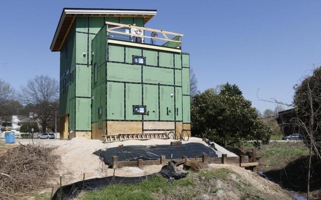 A new three story, 1,700 square foot single family modernist house is being constructed at 301 Wade Ave. in Raleigh, close to where Wade Avenue feeds into Capitol Boulevard just north of downtown. Seen from its back side, a creek meanders around three sides of the new home on a 5/8th acre lot owned by 33-year-old Marshall Davis; the house, designed by his retired architect father Walter Davis, 68, is being built jointly by the Davises.