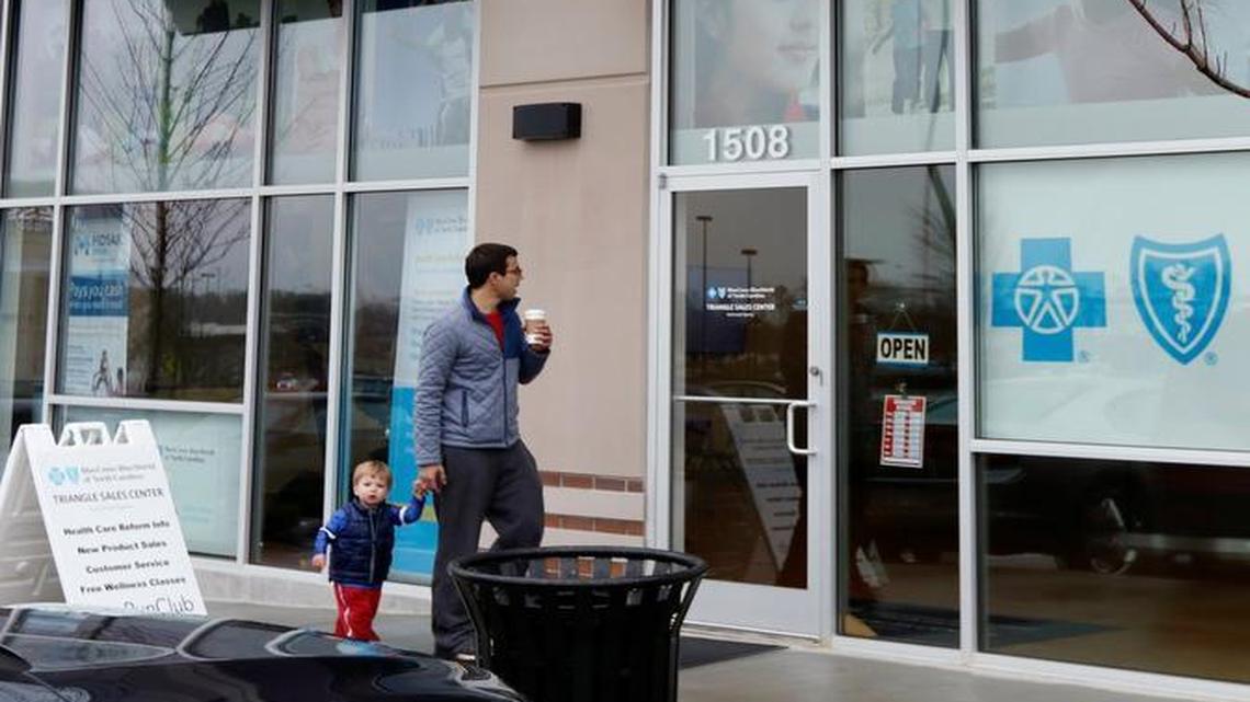 A father and son pass by the Blue Cross Blue Shield of North Carolina Triangle Sales Center in the Village Market Place shopping center in Morrisville, NC Saturday, January 9, 2016. BCBS NC customers who have had trouble enrolling in the Affordable Care Act (ACA) will get an extension on enrollment to take care of a computer glitch that prevented enrollments or enrolled clients in the wrong plan.