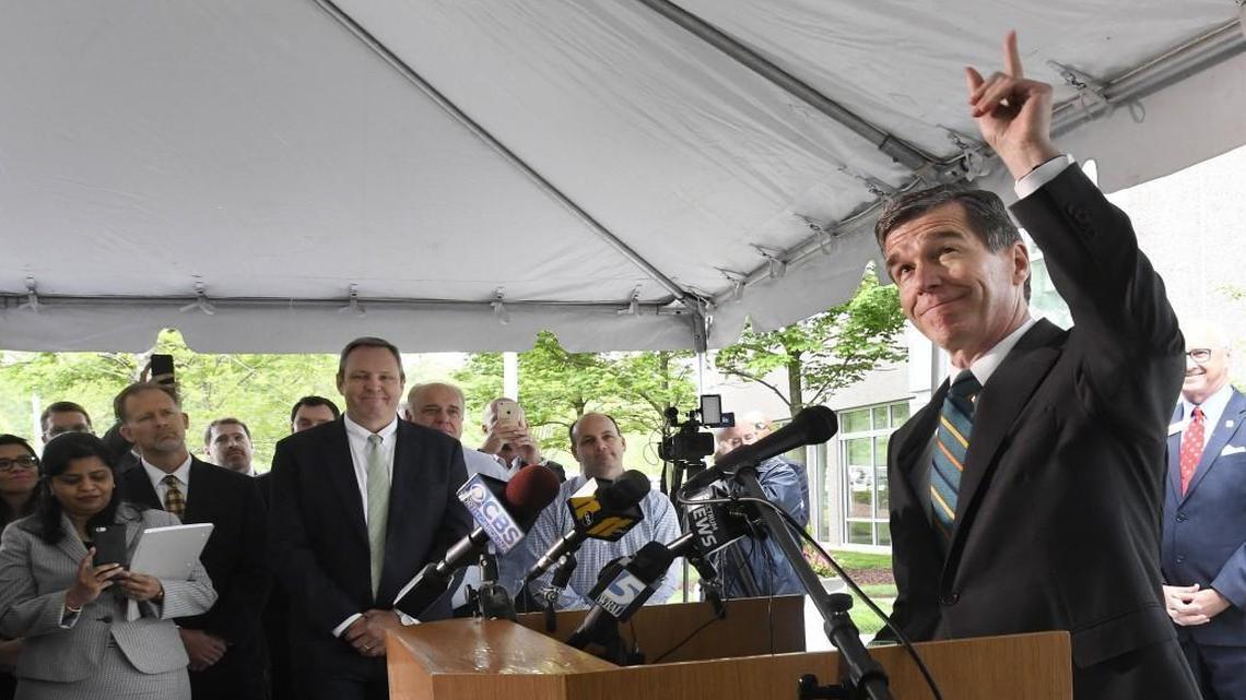 N.C. Gov. Roy Cooper points to the sky and comments on the rain as he speaks during an announcement at the Credit Suisse campus in Research Triangle Park on Tuesday. The company which has 1,500 employees in RTP and Morrisville, announced it will add 1,200 jobs to its Triangle operation.