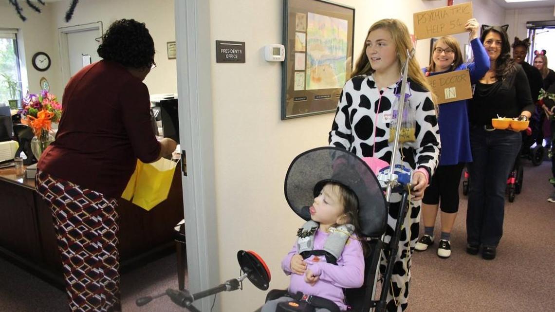 Volunteers from Raleigh Charter High School take Tammy Lynn Center clients trick-or-treating last month. Here, TLC executive assistant Joyce Murphy gives candy to Riley Rushin.