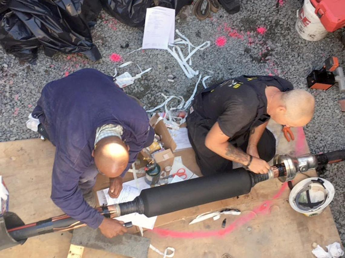 New River Construction crew splices a severed cable on Hatteras Island. The company is the electrical contractor for Cape Hatteras Electric Cooperative, which supplies power to Hatteras Island and owns the damaged transmission line.