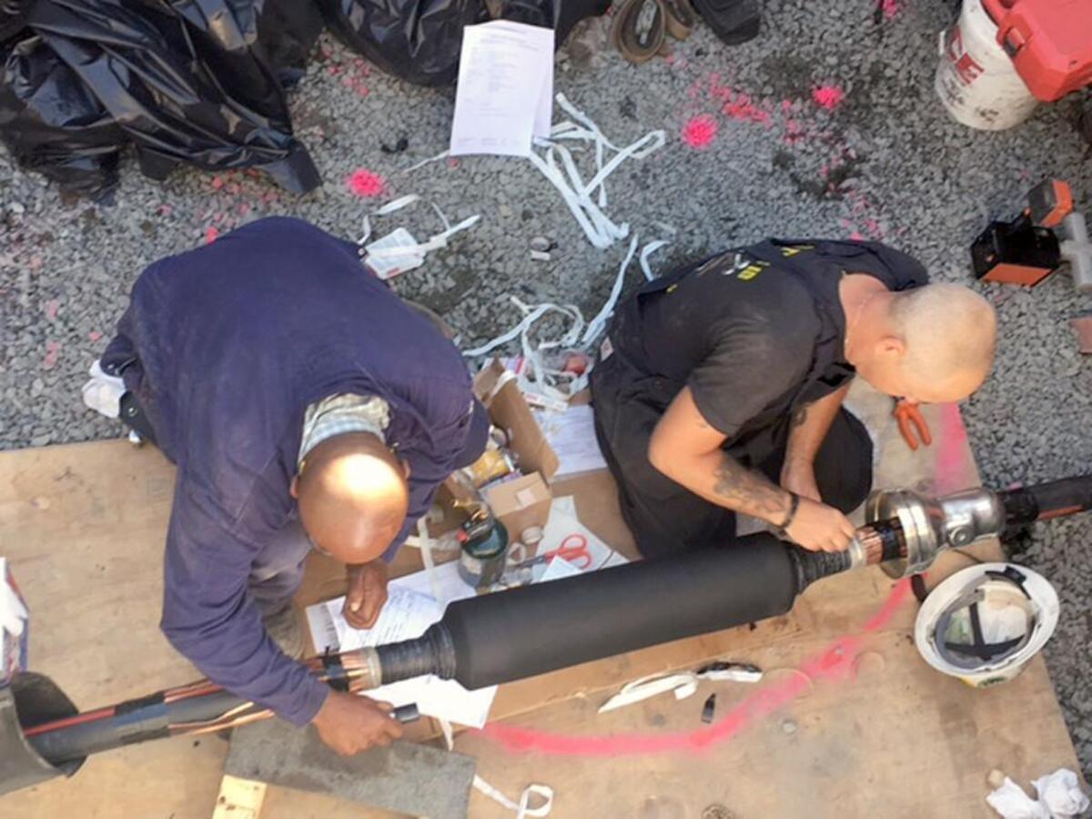 New River Construction crew splices a severed cable on Hatteras Island. The company is the electrical contractor for Cape Hatteras Electric Cooperative, which supplies power to Hatteras Island and owns the damaged transmission line.