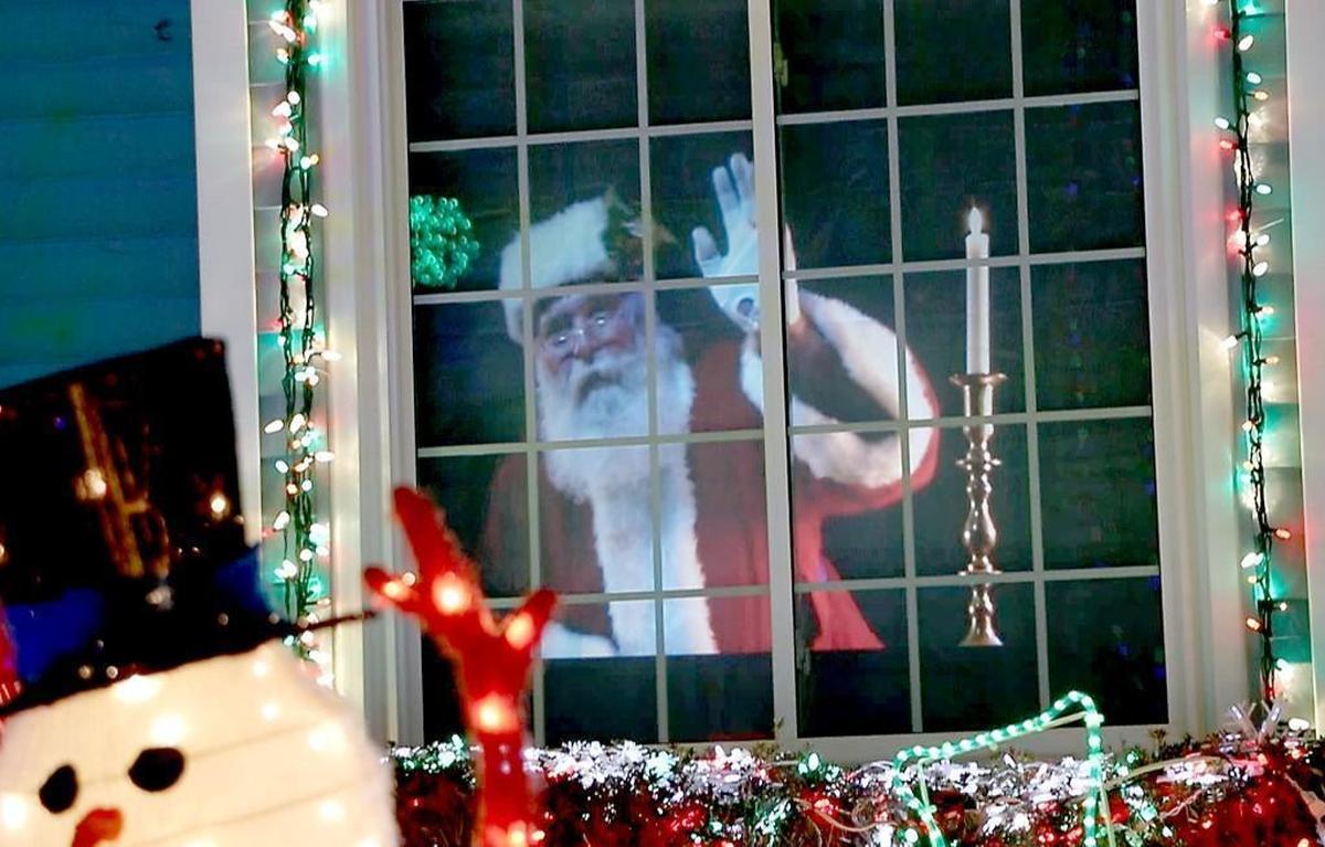 A projection of Santa in the window appears to wave at passerby at the home at 2216 Abbey Lane in North Raleigh.