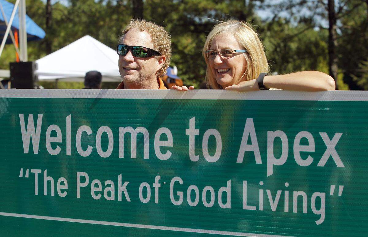 Apex residents pose with a town road sign in 2015, during a celebration with music, rides, games, food trucks, entertainment, activities and municipal services exhibits.