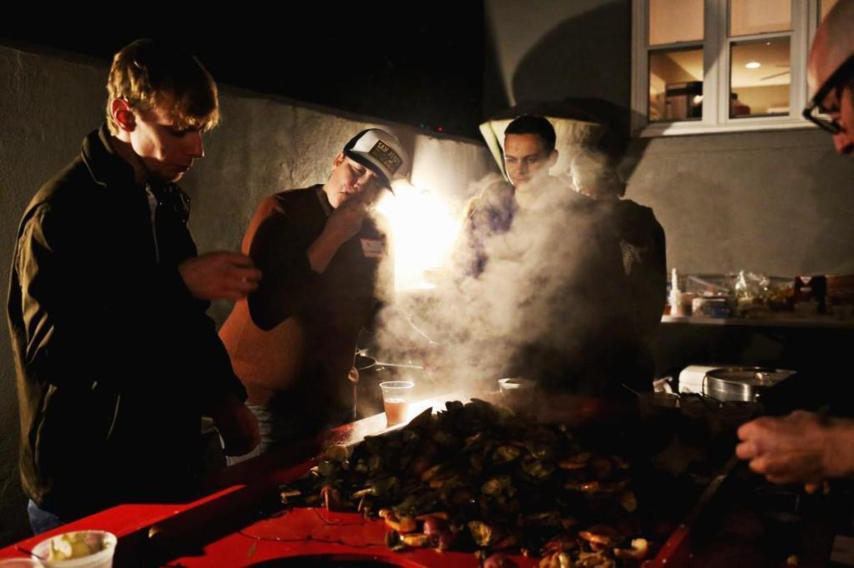 Chef Ashley Christensen, second from left, eats from a low country boil alongside guests at her Raleigh home Oct. 30, 2017, during an industry mixer.