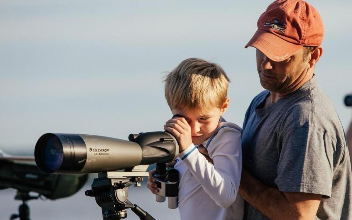 Miles Jeffer, left, gets a boost from his father, Herman Jeffer, right, to look through a telescope at a bald eagle during an eagle count at Jordan Lake in Apex, N.C. on Sunday, July 10, 2016.
