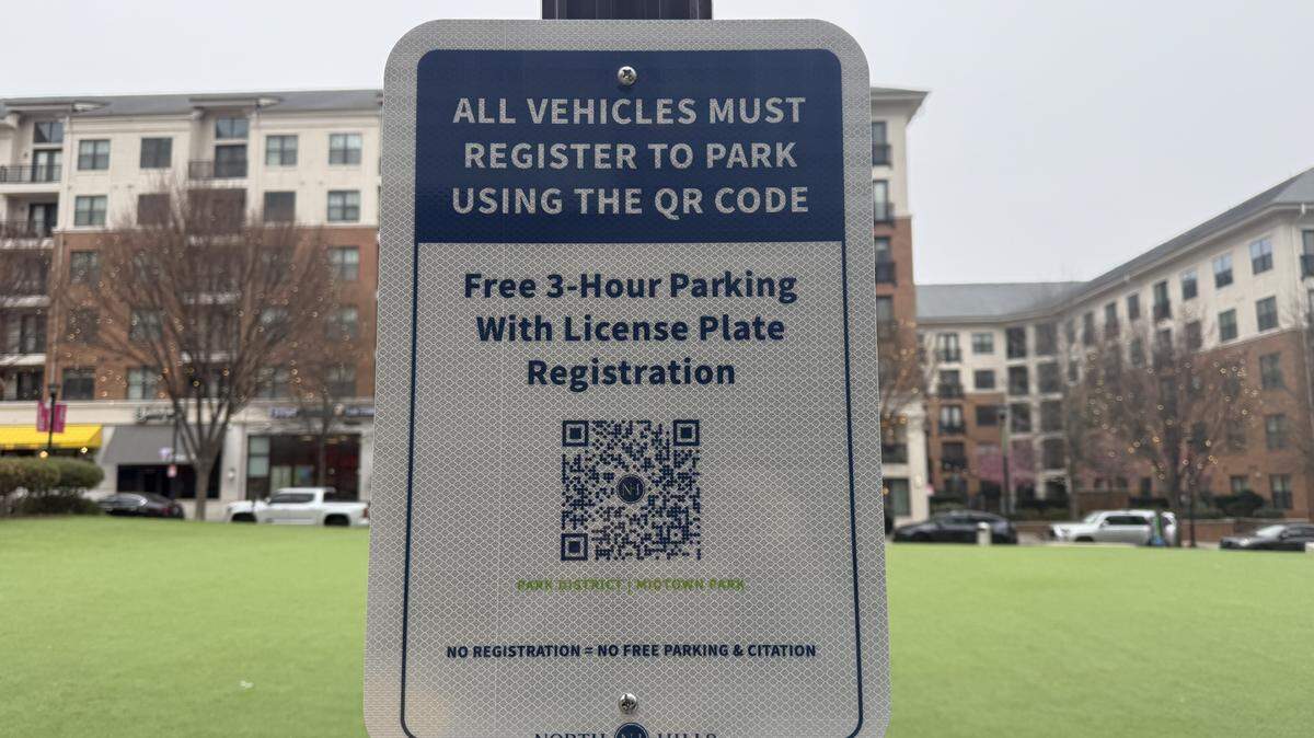 Signs with QR codes posted along Midtown Park in the North Hills Park District prompt visitors to register their vehicles to park.