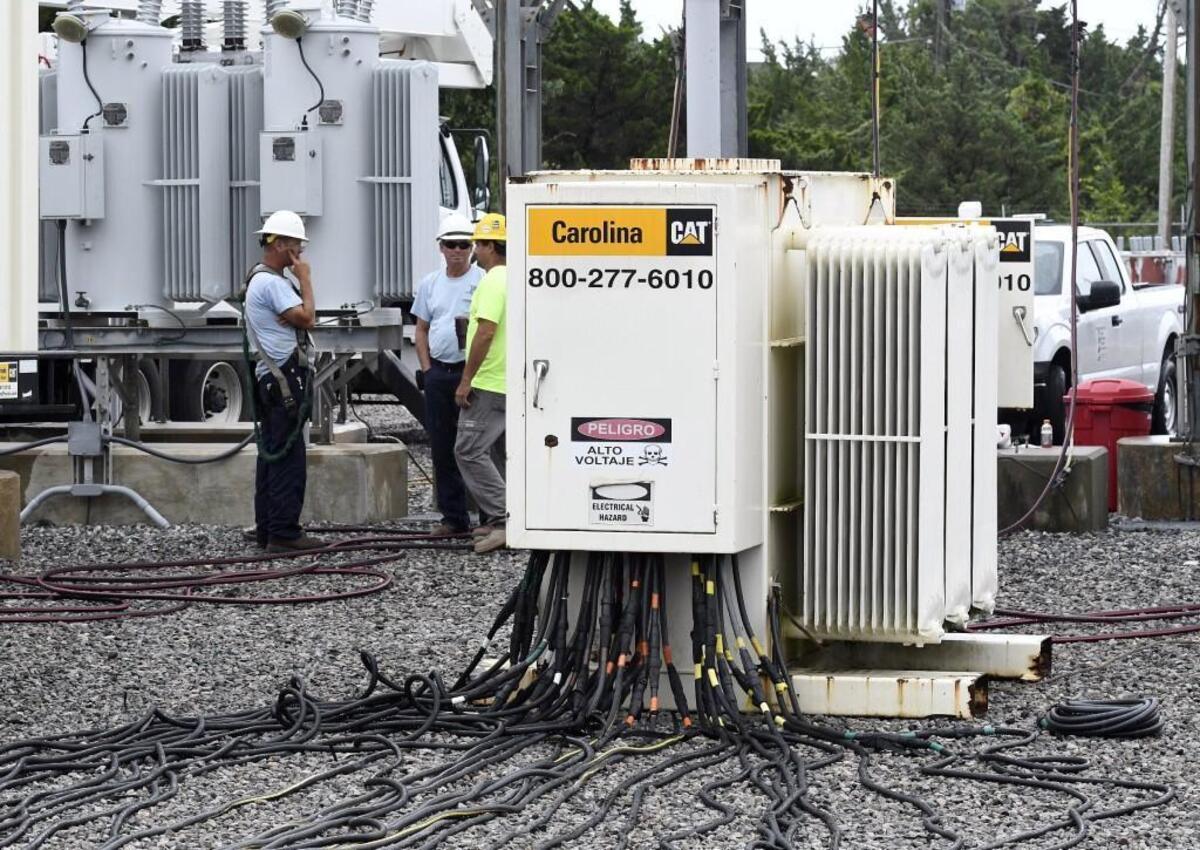 Cape Hatteras Electric Cooperative workmen keep watch on generators at the Avon substation on Hatteras Island in North Carolina, Saturday, July 29, 2017. The workers monitor the power levels and make sure the generators have fuel. The wires snaking to the junction box are feeding power to the electrical grid so residents may return to a somewhat normal life after a construction crew cut the main electrical cable to Hatteras Island Thursday morning.