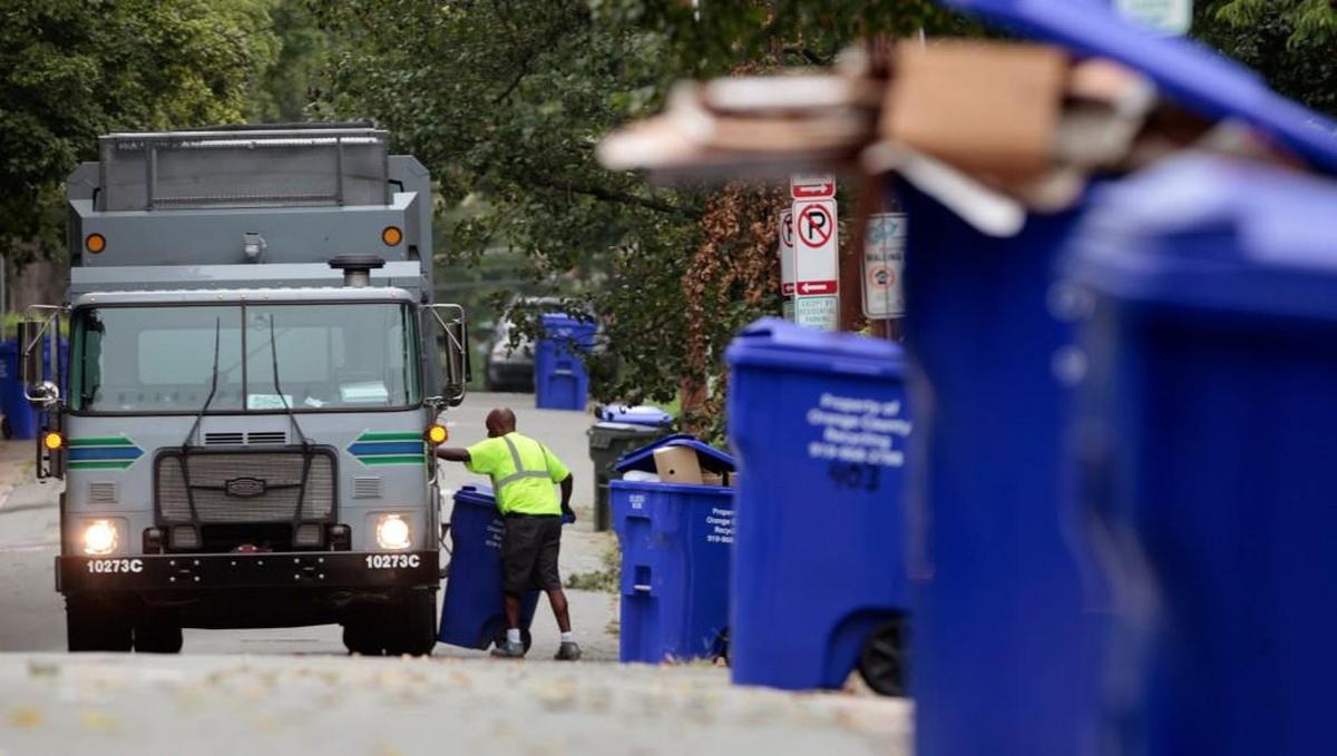 An Orange County recycling employee empties a long row of blue rollcarts along Lindsay Street in Chapel Hill in this 2014 photo. 