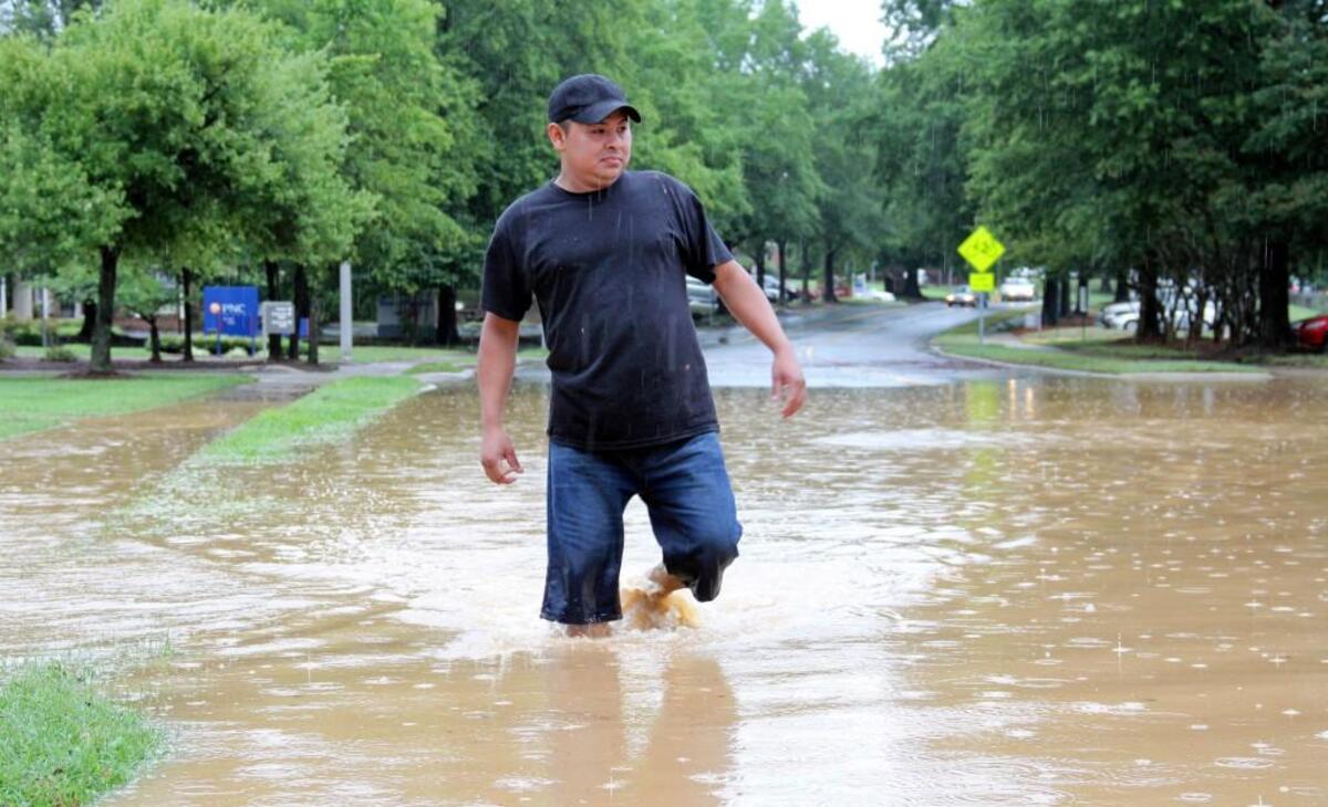 Sender Castillo of Chapel Hill wades in water up to his knees on Willow Drive next to University Mall in Chapel Hill on Sunday, June 30, 2013. Castillo was trying to return to his Camelot Village apartment on Estes Drive. Police blocked the entrance as they evacuated residents from the flooded complex. An officer said the water inside the complex was chest deep.