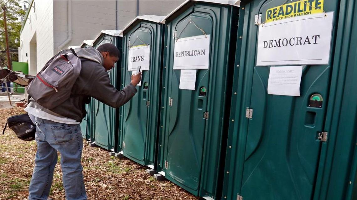 Khalif Ruebin of Durham stopped to take some smartphone photos of seven porta-potties labeled White, Colored, Men, Ladies, Trans, Democrats and Republicans Wednesday, April 6, 2016 before attending an HB2 protest next door at the Bull City Cool Food Hub at 902 North Mangum Street, Durham, NC highlighting the changing history of social policy and bathroom norms. About 50 Durham area residents attended the protest session inside of the Hub.