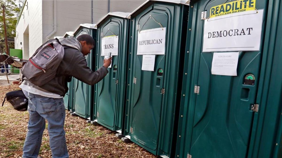 Khalif Ruebin of Durham stopped to take some smartphone photos of seven porta-potties labeled White, Colored, Men, Ladies, Trans, Democrats and Republicans Wednesday, April 6, 2016 before attending an HB2 protest next door at the Bull City Cool Food Hub at 902 North Mangum Street, Durham, NC highlighting the changing history of social policy and bathroom norms. About 50 Durham area residents attended the protest session inside of the Hub.