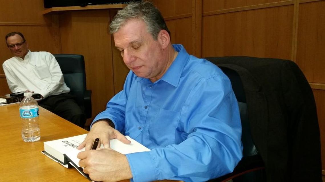 John Feinstein, right, signs a copy of his boo “The Legends Club” during a stop Wednesday in Raleigh.