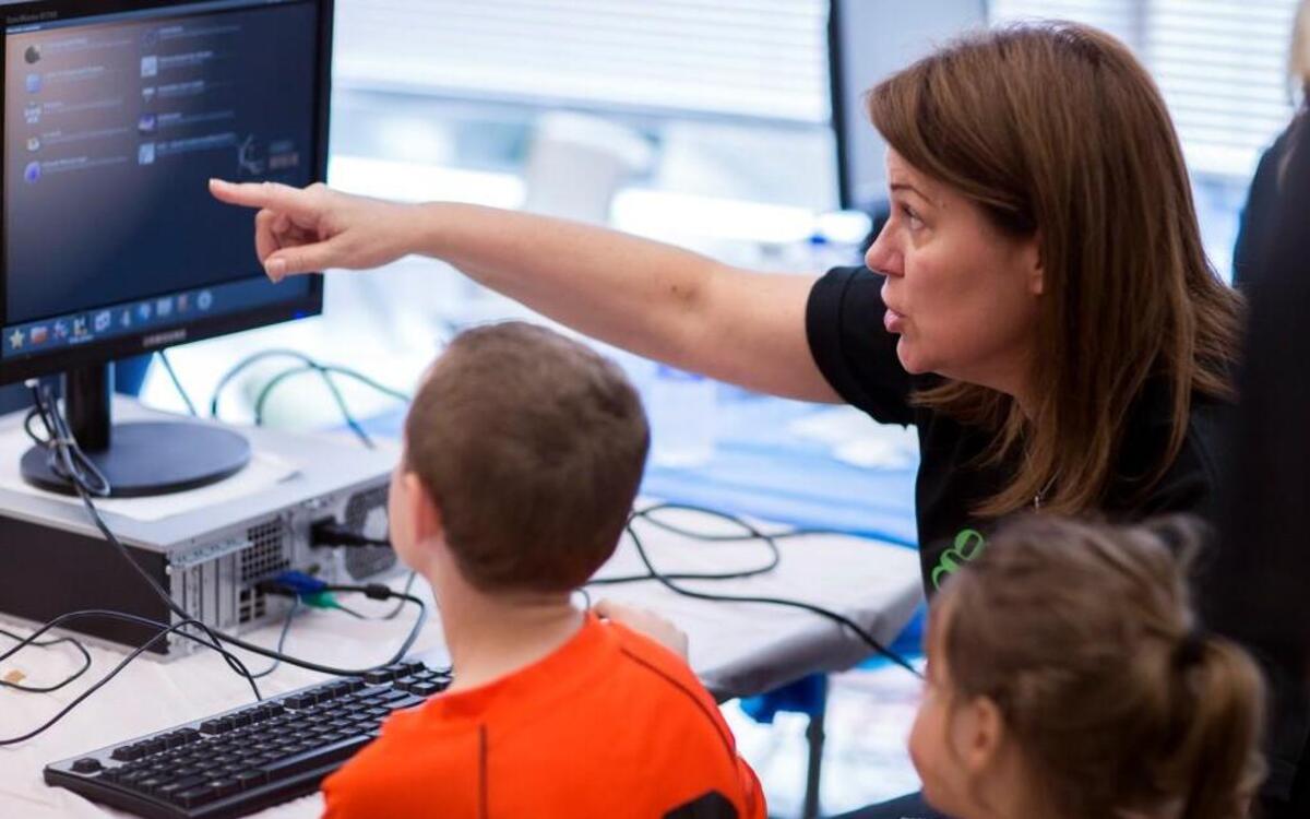 A MetLife employee demonstrates the Ubermix operating system on a computer to students at a Kramden Institute Geek-A-Thon in 2014. At the events employees of a sponsoring company refurbish computers for local students.