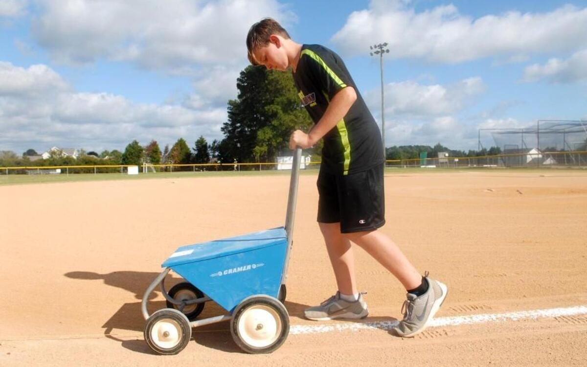 Derrick Collins, 13, chalks the lines of one of the few softball fields in the Cleveland community on September 26, 2017. Collins and his sister, Mckenzie, 11, help out at the fields to partially pay for their membership in the Greater Cleveland Athletics Association.