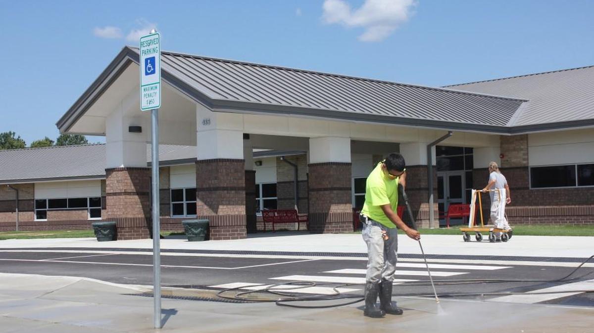 
Ray Escalera power washes the sidewalk outside the new North Johnston Middle School. Debt approved by voters in 2013 funded $57 million in capital projects, including construction of the new school in Micro. In 2016, the school board hopes to have another round of bonds on the ballot.
