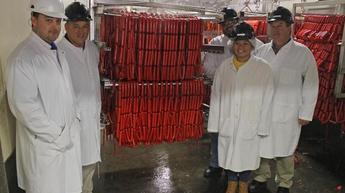 From left, employees Kurt Byrd, Johnny Hayes, Chris Moore, Sunni Queipo and Donnie Moore stand next to a rack of Bright Leaf hot dogs in the Smithfield plant.