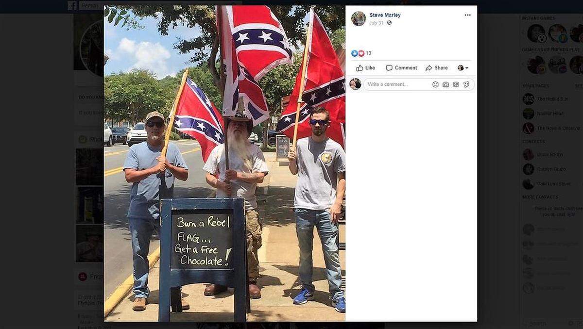 Confederate flag supporters pose with a sign that Matthew Shepherd, owner of Matthew’s Chocolates in downtown Hillsborough, put out in response to their protest. The photo went viral, promptly angry responses and death threats from people nationwide.