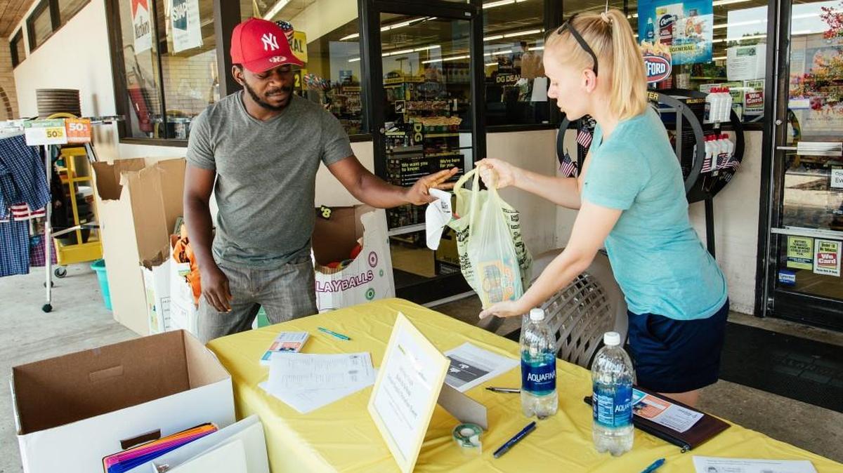 Ola Samuel hands a bag of school supplies to Jillian Knight, a volunteer for Raleigh Rescue Mission, during a school-supply drive outside Dollar General in Raleigh, N.C., on Saturday, July 22, 2017.