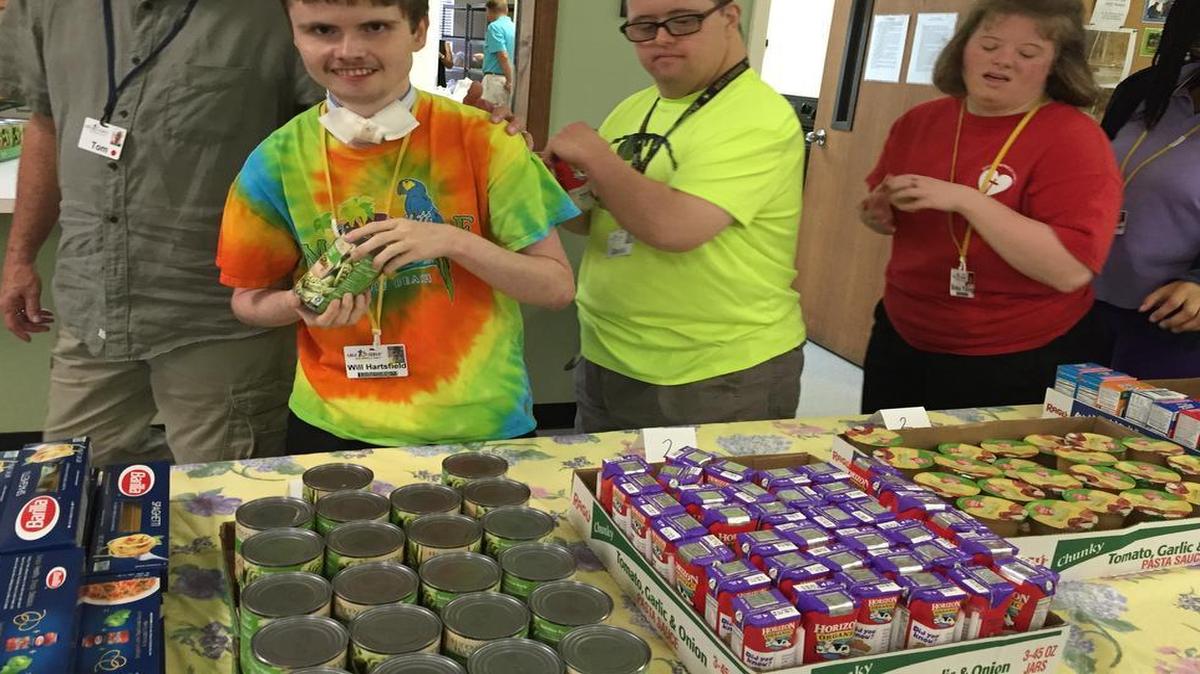 Able to Serve participants Will, David, and Becka assemble food for a Backpack Buddies service project.