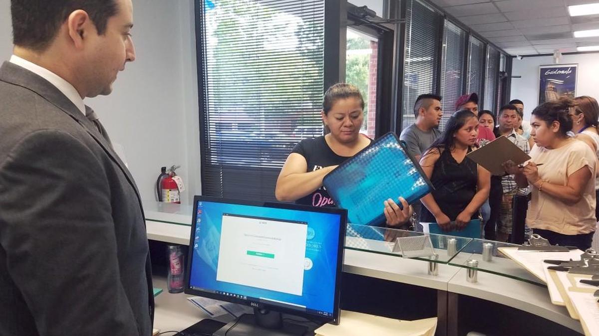 Ruth Castañeda, 36, was the first in line at the Consulate General of Guatemala in Raleigh on Monday morning. Jorge R. Archila, consul of the Raleigh Guatemalan consulate, left, was at the counter checking people in. Castaeda was waiting for the doors to open at 8 a.m. to start the paperwork for passports for her two children in Guatemala.