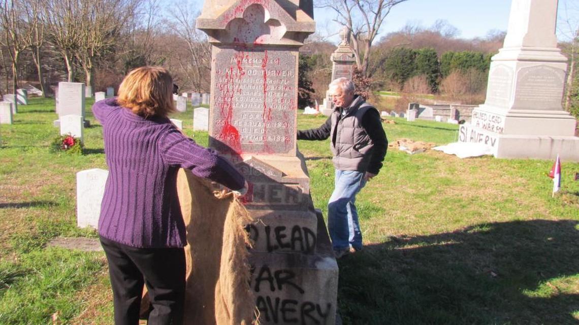 Robin Simonton, executive director of Oakwood Cemetery, and Raleigh historian Bruce Miller work to cover graffiti painted on nine grave markers and monuments, mostly in the Confederate section. Damage is estimated at $20,000.
