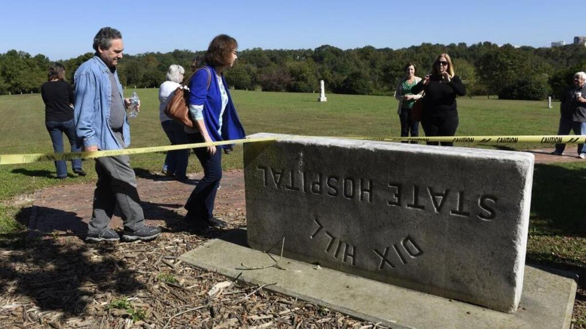 Gary Fried, left, and Susan Watts examine a stone sign that was flipped over and reused when the state hospital was renamed while on a trolley tour of Dorothea Dix in Raleigh, N.C. on Sunday, October 16, 2016. Fried says he worked in different capacities on Dix from 1998-2010.