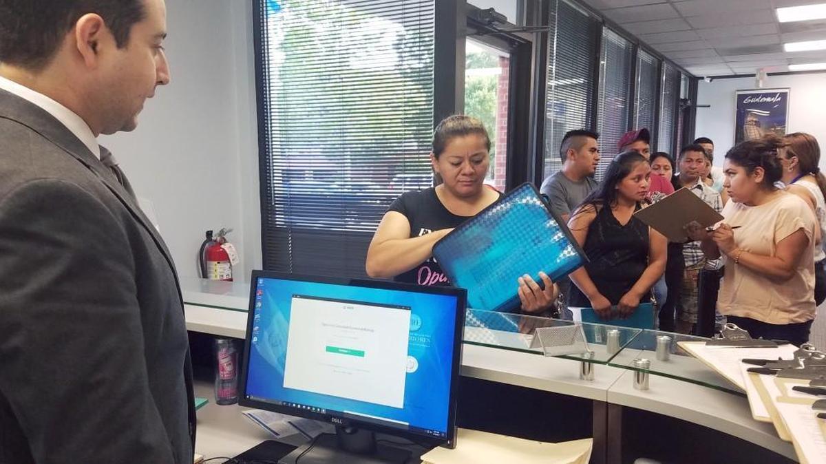 Ruth Castañeda, de 36 años, fue la primera persona en la fila del Consulado General de Guatemala en Raleigh el lunes en la mañana. Jorge R. Archila, cónsul del consulado guatemalteco en Raleigh, izquierda, asistió a la gente mientras entraban. Castañeda esperaba que se abrieran las puertas a las 8 a.m. para tramitar los pasaportes de sus hijos en Guatemala.