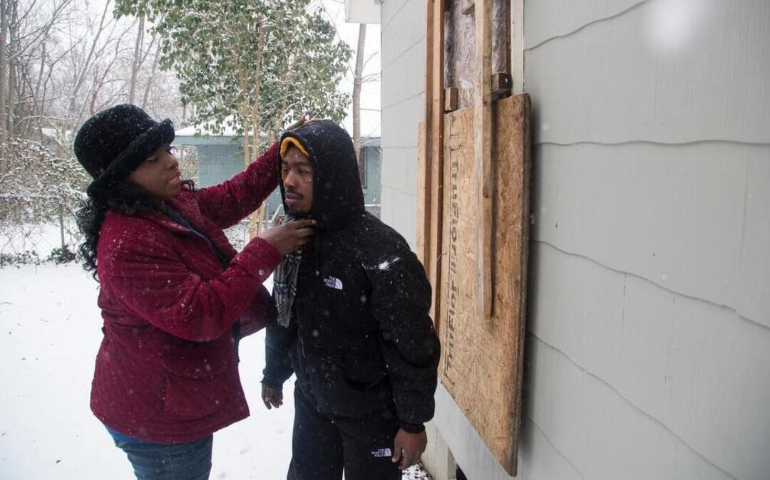 
Renee Pinkney adjusts her son Dontay Jones' jacket in the backyard of the home where Dontay lived for months under Wake County's guardianship. A Raleigh city housing inspector found the building to be substandard and lacking proper heat in November, but the housing case still was unresolved three months later. Jones and his roommate are wards of the county due to mental illness.
