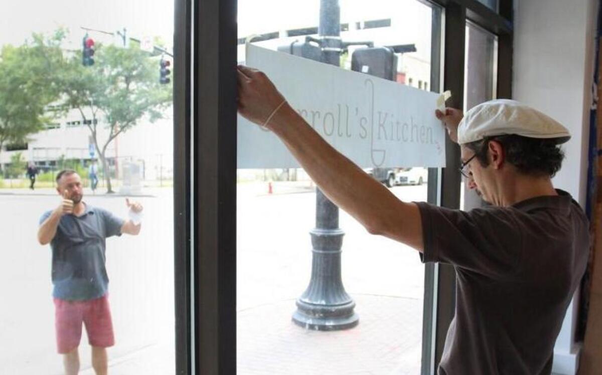 Shawn Webb, right, hangs a sign at Carroll’s Kitchen in downtown Raleigh on Aug. 16, 2016, while Brian Hoppmann makes sure the lettering is straight. The restaurant will provide jobs for formerly homeless women.