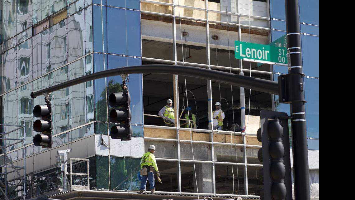 
Construction workers in the Charter Square Building watch a small group of advocates gather on Tuesday in Raleigh for a memorial service for those who died in the scaffold collapse at Charter Square last month, 
