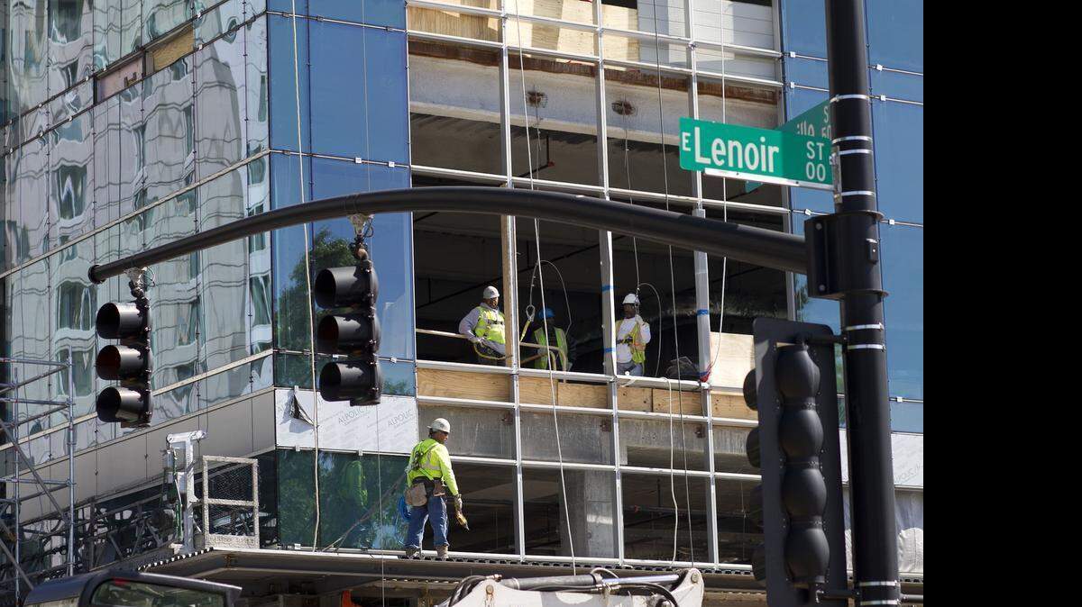 
Construction workers in the Charter Square Building watch a small group of advocates gather on Tuesday in Raleigh for a memorial service for those who died in the scaffold collapse at Charter Square last month, 
