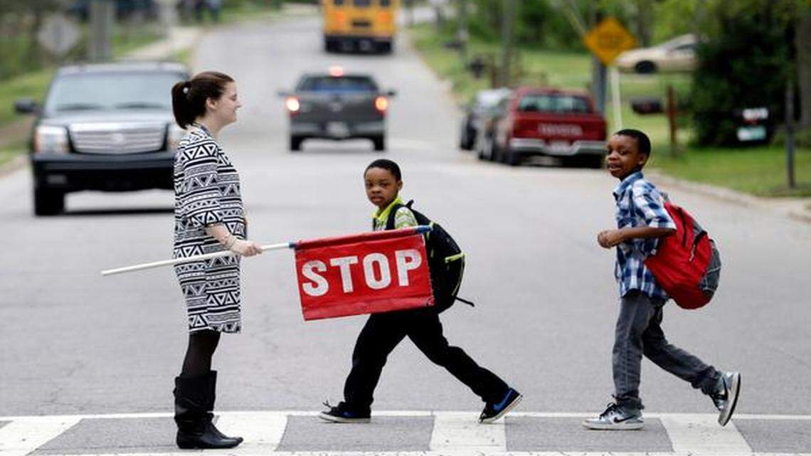 
Teacher Laura Stiegler stops traffic so students can cross the street on Ingram Drive near Brentwood Magnet Elementary School in Raleigh on April 14, 2015. Raleigh is considering putting crossing guards at all elementary and middle schools; they are currently only at about one third of the schools. 
